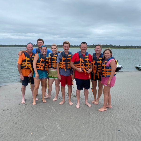 a group of people standing on a beach posing for the camera