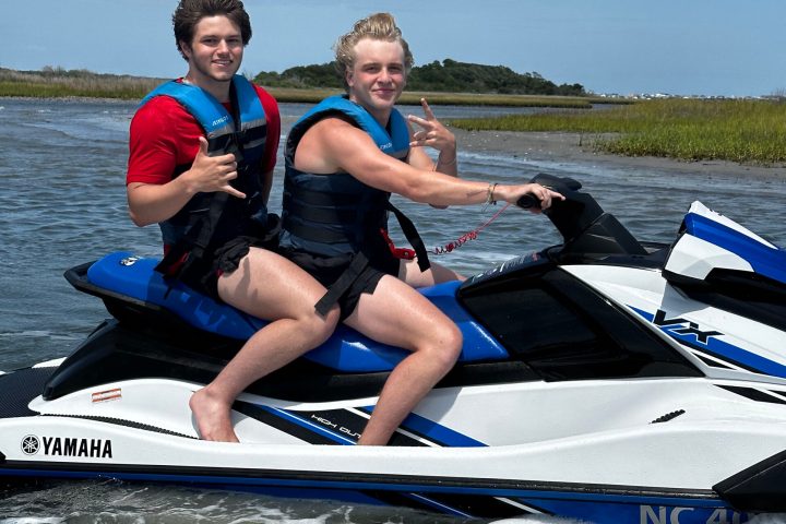 a group of people riding on the back of a boat in the water