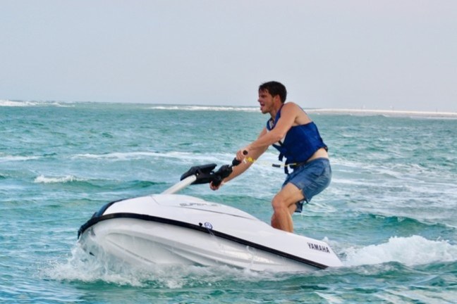 a man riding on the back of a boat in the water